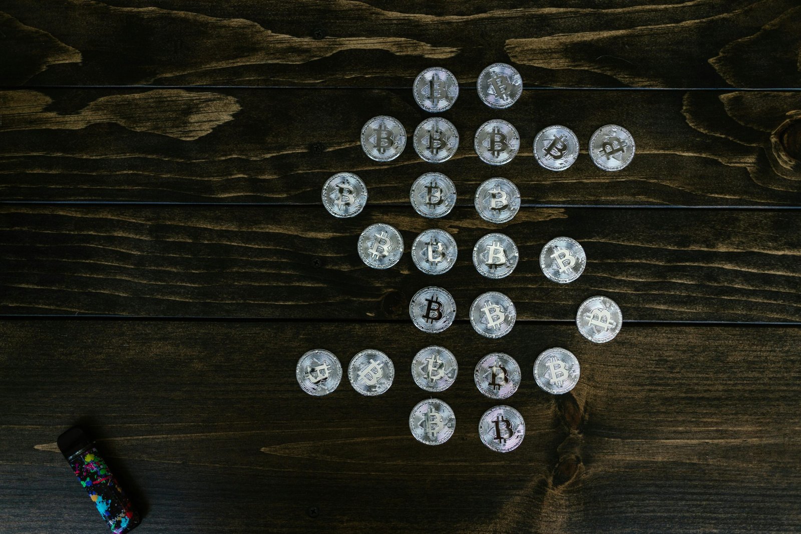 Flat lay of Bitcoin coins arranged in a shape on a wooden surface representing digital currency.