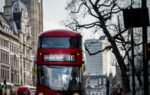 A classic red double-decker bus traveling on a busy street in London, England.