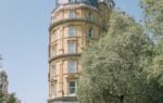 Vertical shot of Corinthia Hotel showcasing London's historic architecture and vibrant city life.