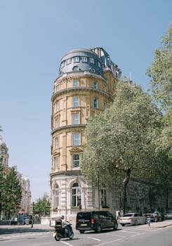 Vertical shot of Corinthia Hotel showcasing London's historic architecture and vibrant city life.