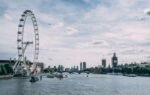 Scenic view of the London Eye on the River Thames with clear blue skies and city skyline.