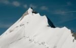 Stunning snow-covered alpine mountain peak against a clear blue sky, showcasing natural beauty.