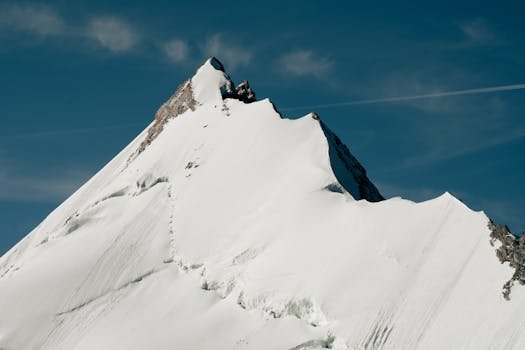 Stunning snow-covered alpine mountain peak against a clear blue sky, showcasing natural beauty.