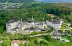 A stunning aerial view of the iconic Dolder Grand Hotel surrounded by lush greenery in Zurich, Switzerland.