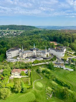 A stunning aerial view of the iconic Dolder Grand Hotel surrounded by lush greenery in Zurich, Switzerland.