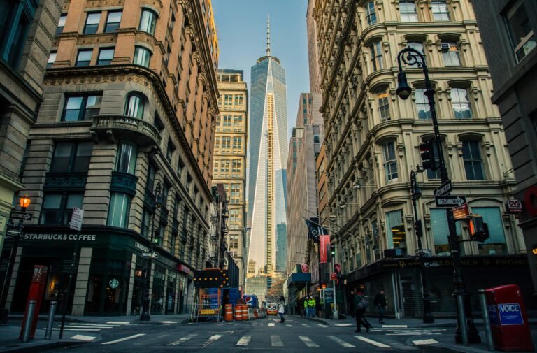 Street view of One World Trade Center in New York City surrounded by urban architecture and city life.
