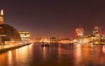 Stunning nighttime view of London's illuminated skyline along the River Thames.