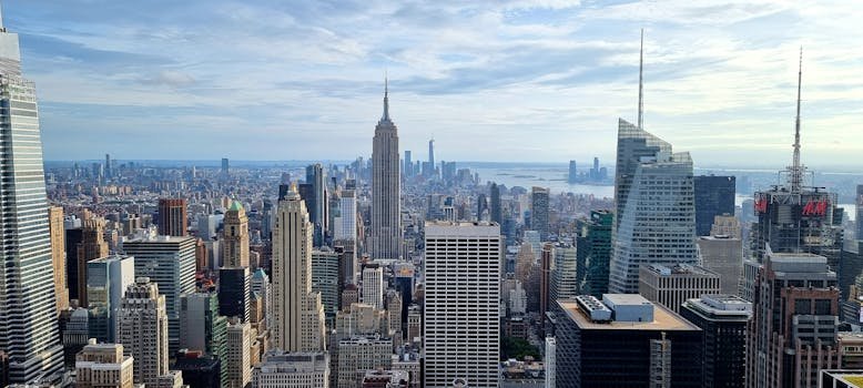 Aerial view of New York City skyline featuring iconic skyscrapers under a cloudy sky.