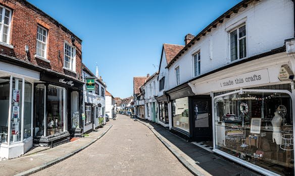 Picturesque view of an empty street in historic Godalming, England with old shops and blue sky.
