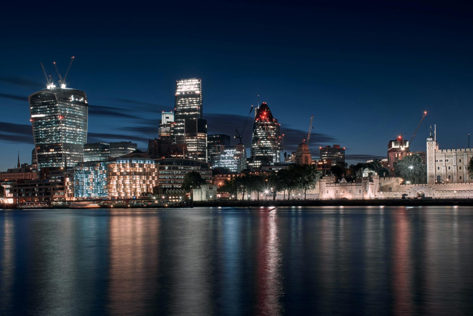 Captivating night view of modern London skyline with reflections on the Thames.
