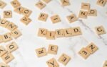 Scrabble tiles forming the word 'YIELD' on a marble surface, symbolizing finance and investment.