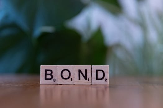 Scrabble tiles spelling 'Bond' on a wooden table with a blurred green background.