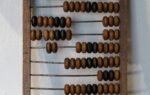 Vintage wooden abacus with brown and black beads on a white background.
