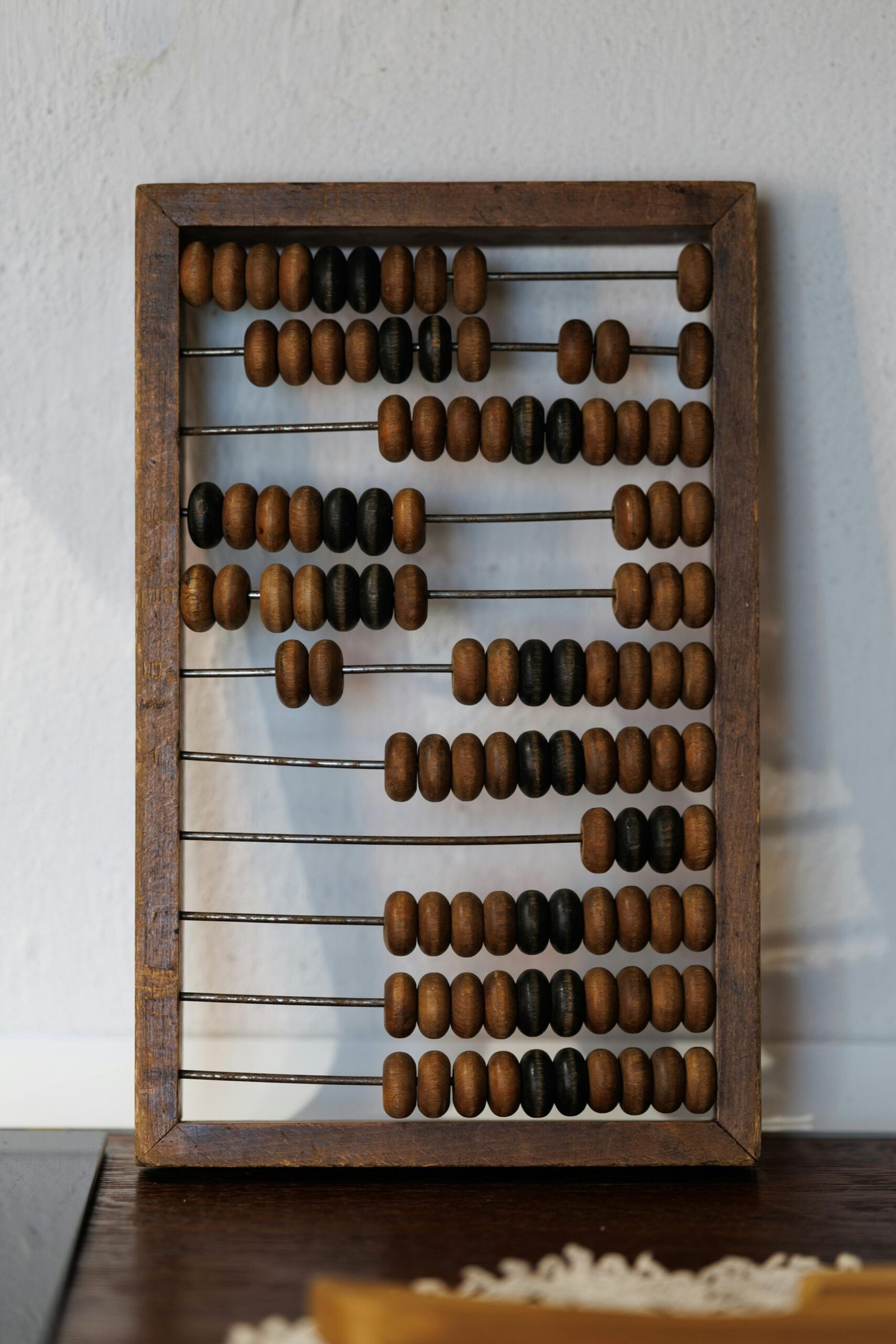 Vintage wooden abacus with brown and black beads on a white background.