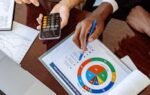 Two business professionals discussing financial documents and strategies at an office desk.