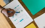 Overhead view of a person analyzing business charts and graphs on paper.
