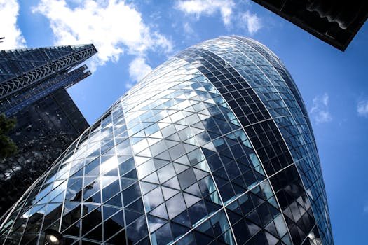 Low-angle shot of modern skyscrapers, featuring glass façades and a clear blue sky.